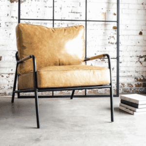 Cozy mustard yellow chair with black metal frame against white brick wall.